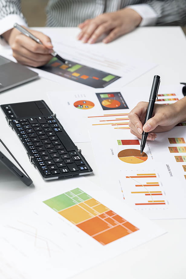 Un groupe de personnes assises à un bureau analysant des documents et des graphiques à des fins de gestion de données