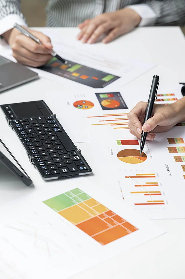 Un groupe de personnes assises à un bureau analysant des documents et des graphiques à des fins de gestion de données
