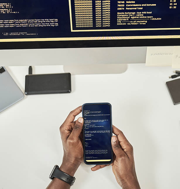 Une personne utilisant un smartphone et un ordinateur sur un bureau