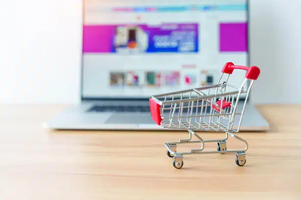 Un caddie de jouets posé sur une table en bois devant un ordinateur portable, soulignant le potentiel du commerce électronique