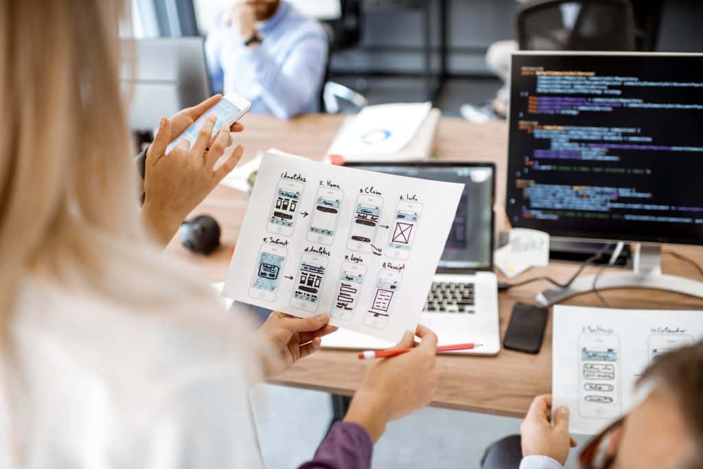 L'entreprise de développement des applications sur mesure regroupe un groupe de personnes assises à un bureau, regardant attentivement une feuille de papier