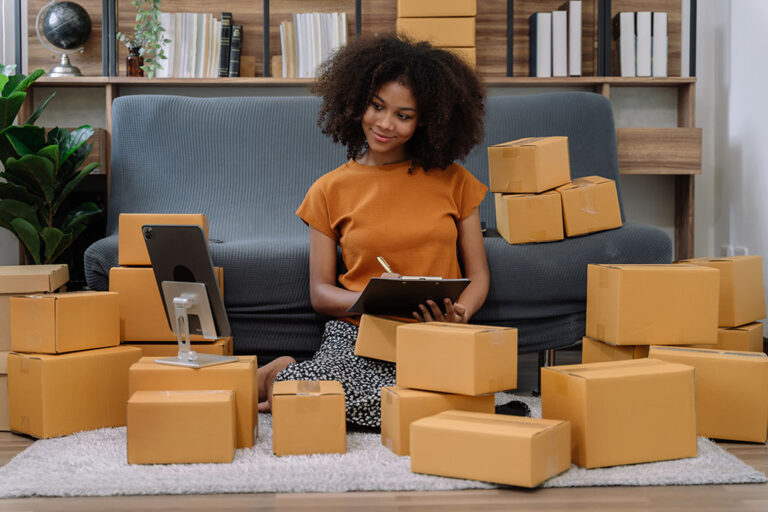 Une femme assise sur un canapé avec des cartons devant elle, parcourant Magento 2