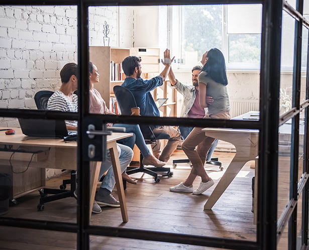 Un groupe de personnes dans un bureau se donnant mutuellement des high fives