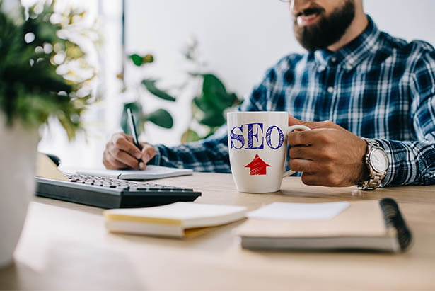 SEO Un homme assis à un bureau avec une tasse de café et un ordinateur portable, travaillant comme expert SEO