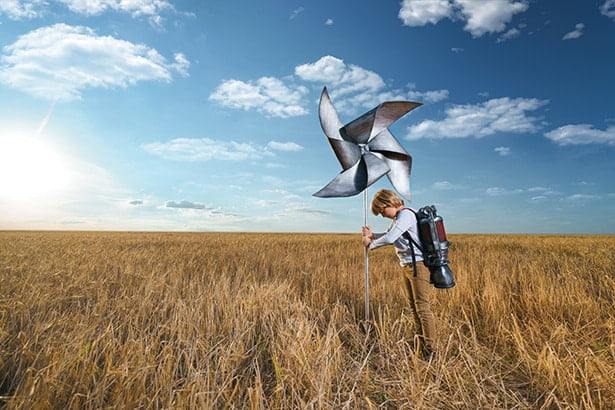 Un garçon se tient debout dans un champ où se trouve une éolienne pour montrer nos succès en développement web