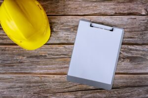Un casque jaune et un presse-papiers sur une table en bois pour Tierce Maintenance Applicative